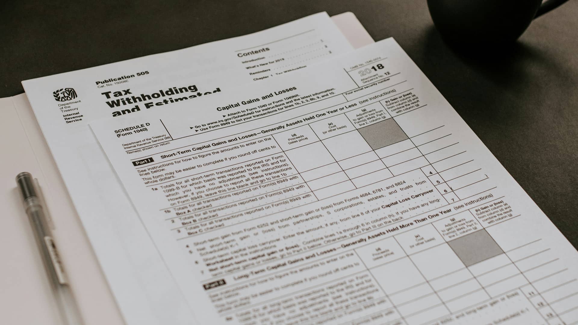 irs tax withholding and capital gains and losses documents on a desk